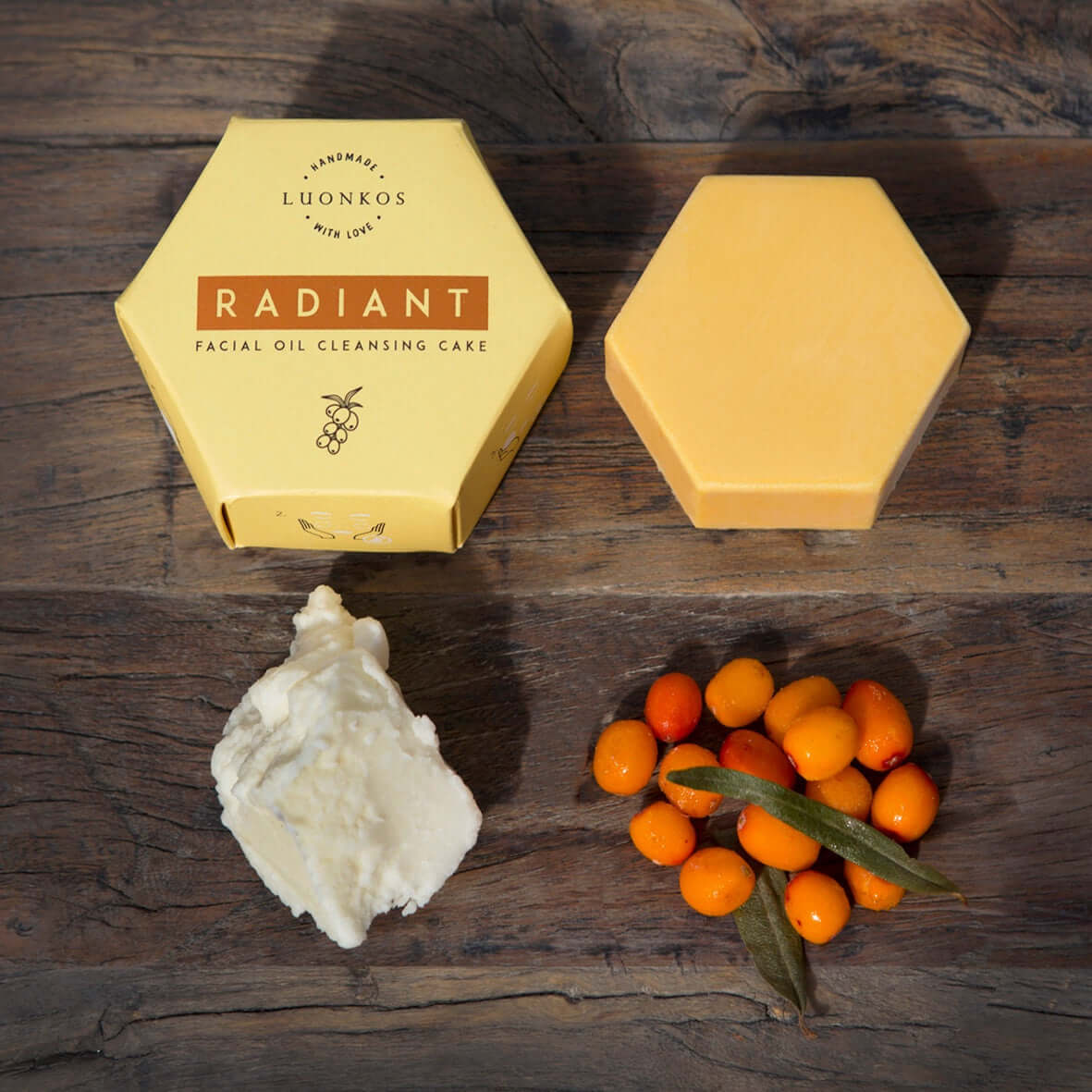 Hexagonal Luonkos Radiant facial oil cleansing cake next to natural ingredients on wooden surface for simple skincare routine