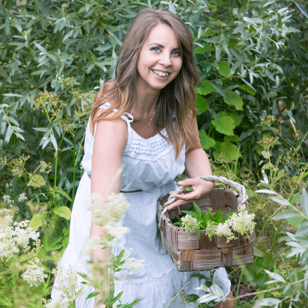 woman in white dress gathering green plants in a wicker basket outdoors with radiant glowing skin hehkuva iho