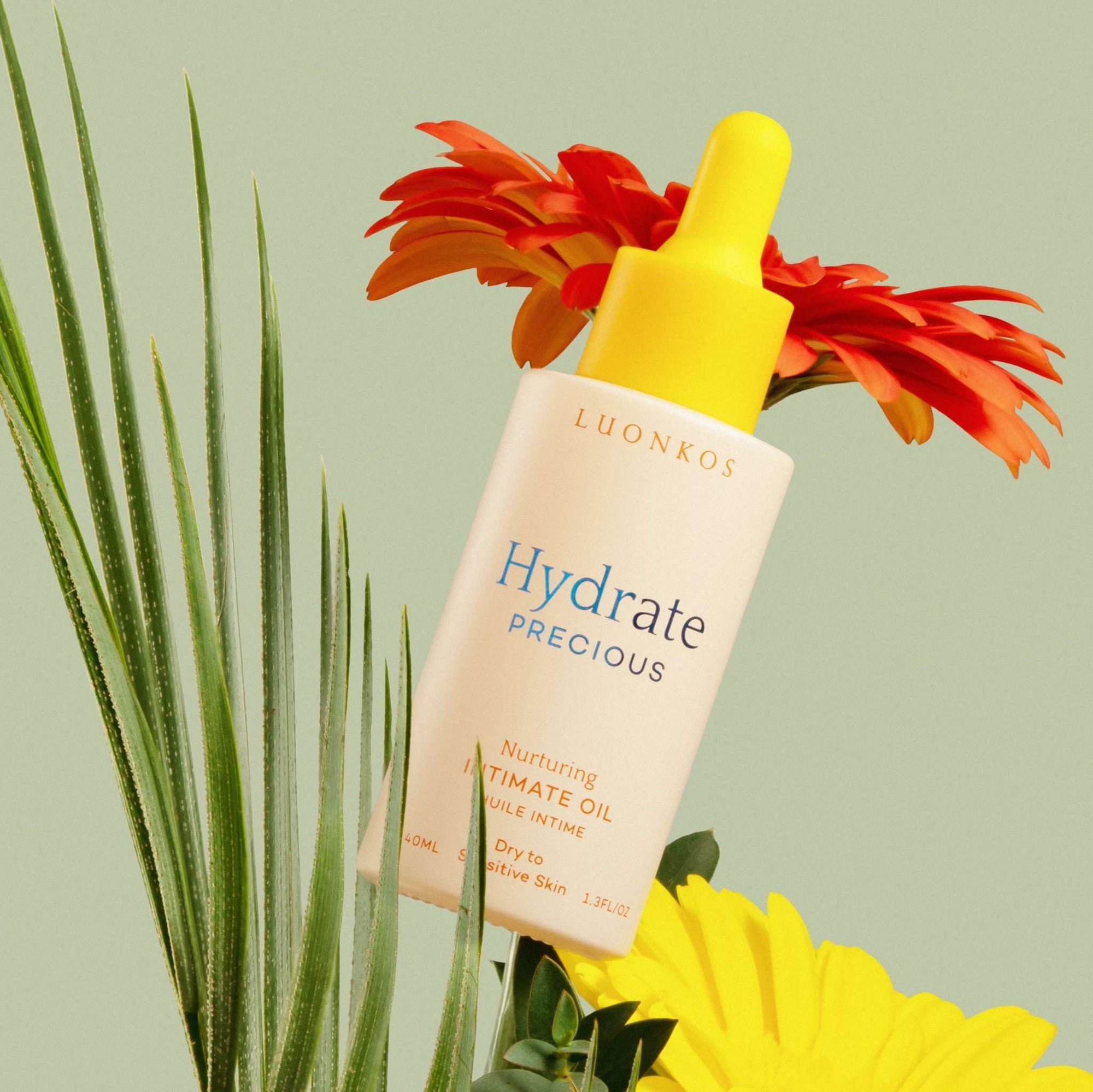 Luonkos Hydrate Precious nurturing intimate oil for dry and sensitive skin with yellow dropper and colorful flowers background, natural menopause skincare product