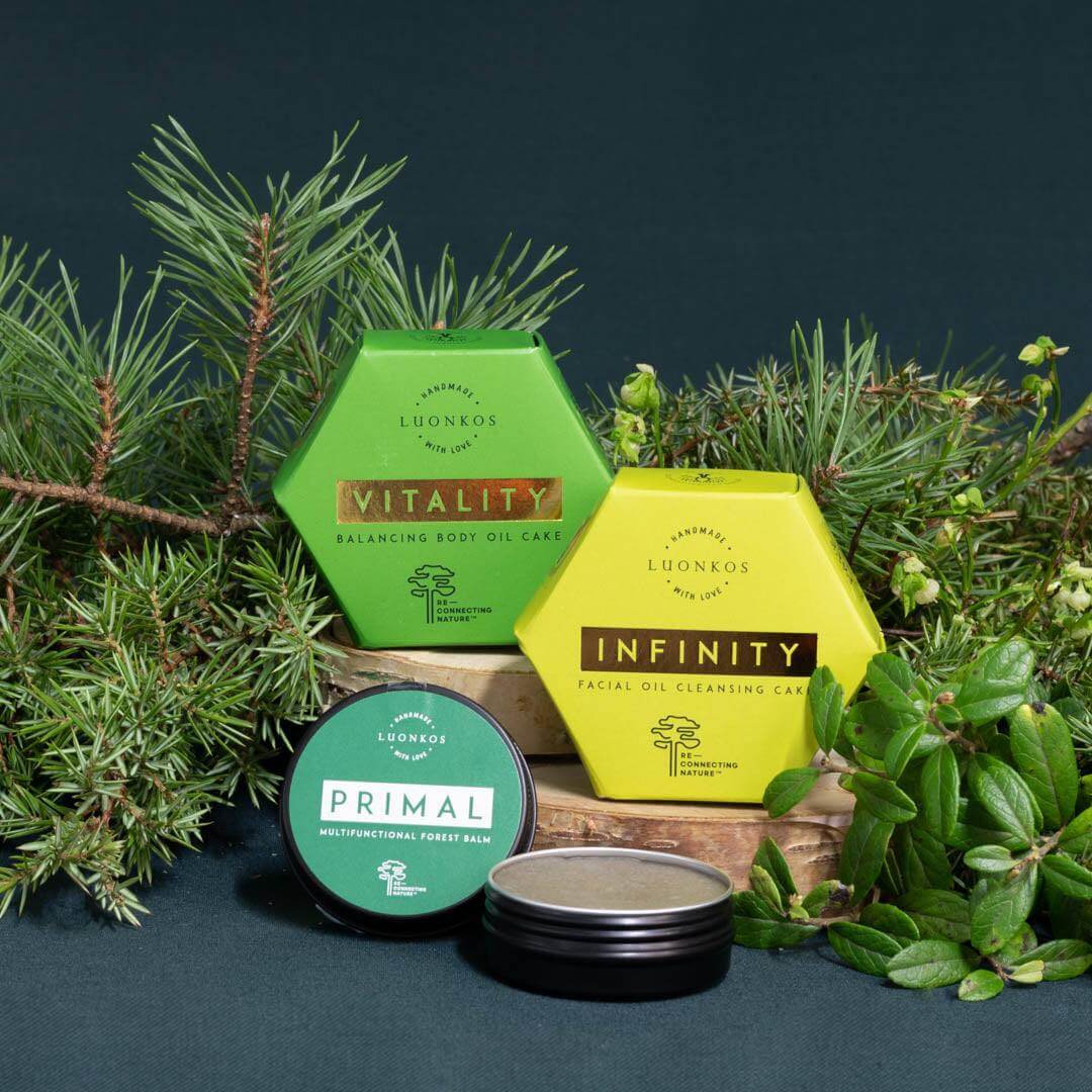 Luonkos Vitality and Infinity oil cleansing cakes and Primal forest balm with natural green pine and herb background for skin care.