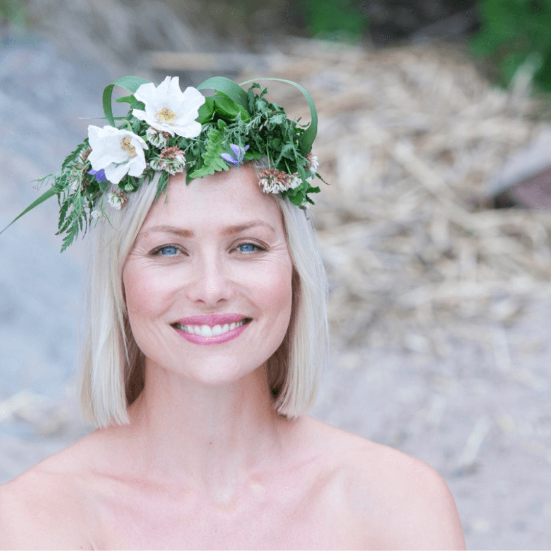Smiling woman with clear glowing skin wearing a floral crown, representing natural summer skincare and kesäinen ihonhoito.