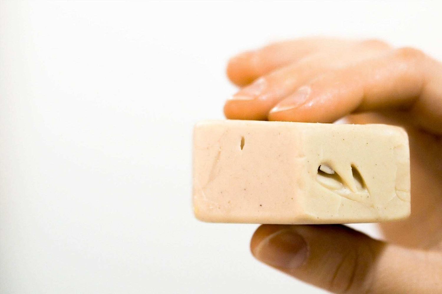 Hand holding a uniquely imperfect natural oil bar representing kakkoslaatu luonnonkosmetiikkaa