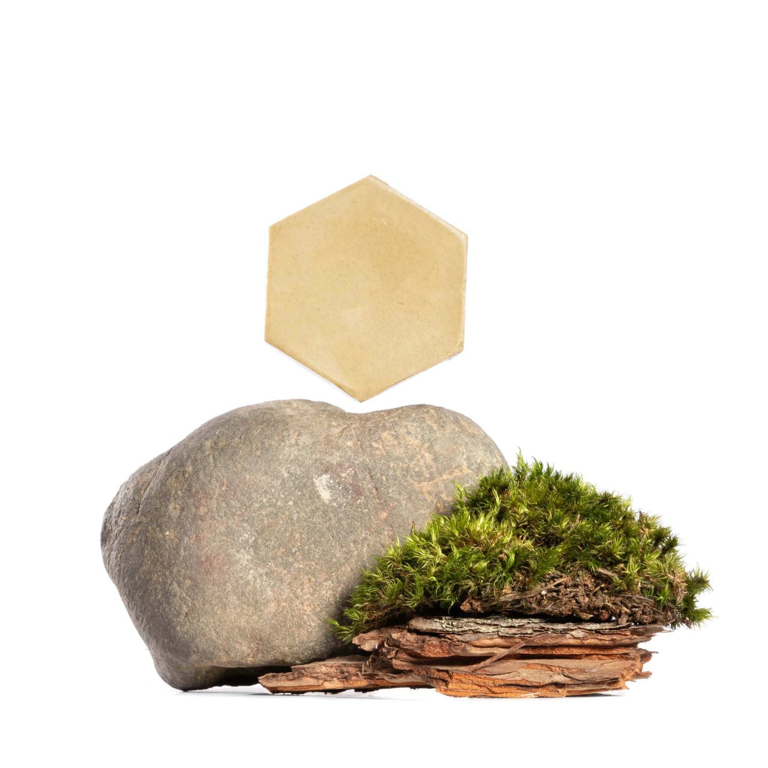 Natural skincare ingredients featuring a hexagonal soap, stone, moss, and bark representing beneficial raw materials for glowing skin in 2025