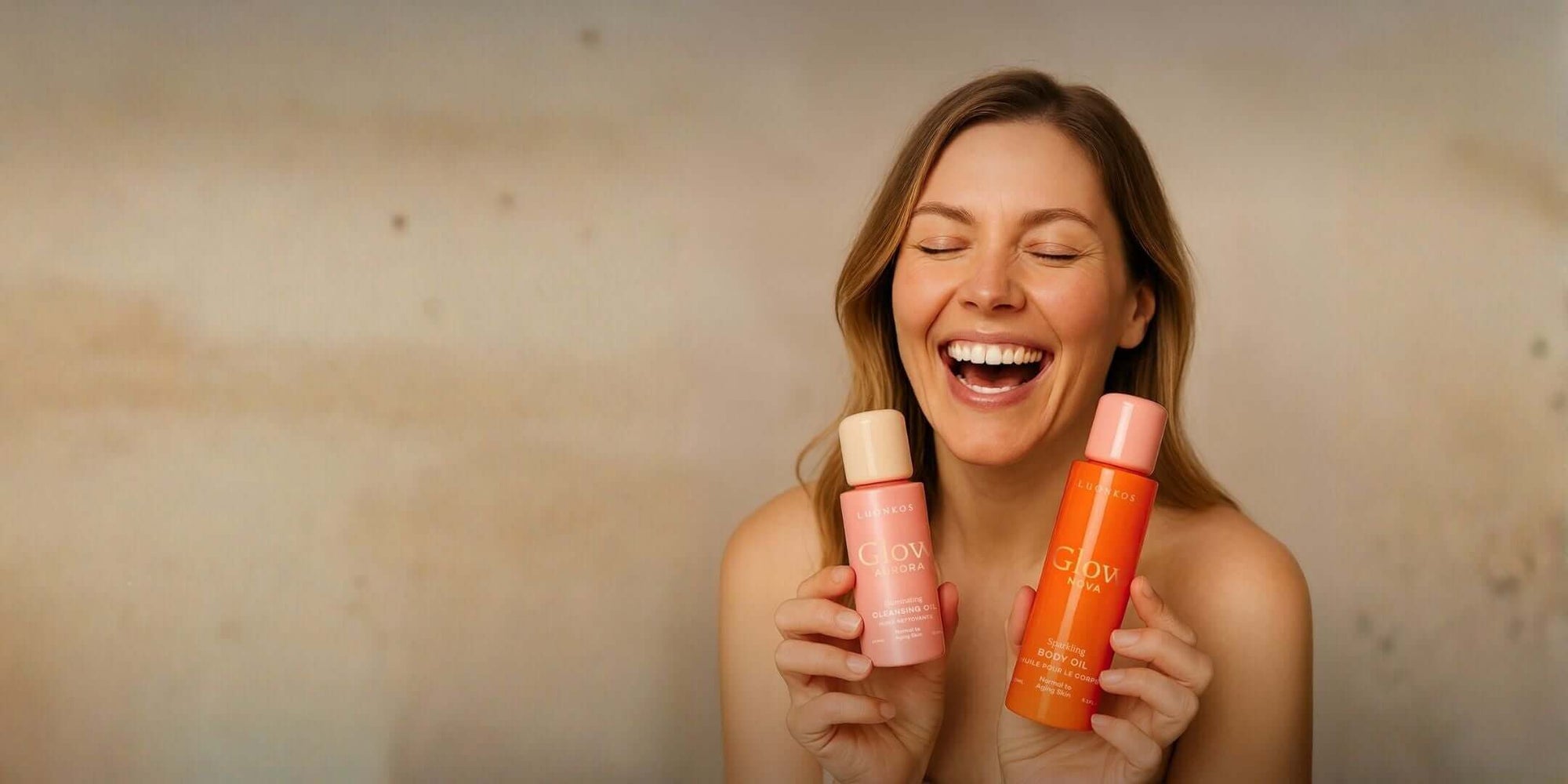 Nainen hymyilee pitäen käsissään Luonkos-öljihoitotuotteita oranssissa pulloissa keväänihonhoitorutiinin esittelyssä.