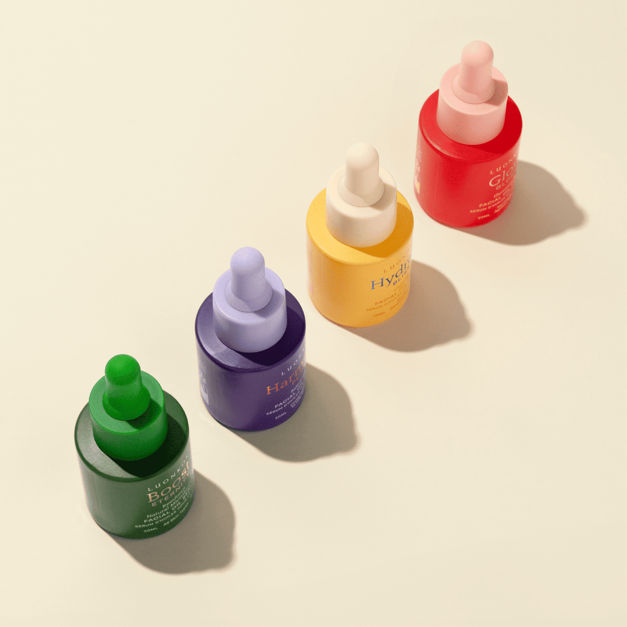 Set of four colorful hexagonal cardboard serum bottles with droppers in green, purple, yellow, and red, showcasing new edgy packaging design for natural skincare serums.