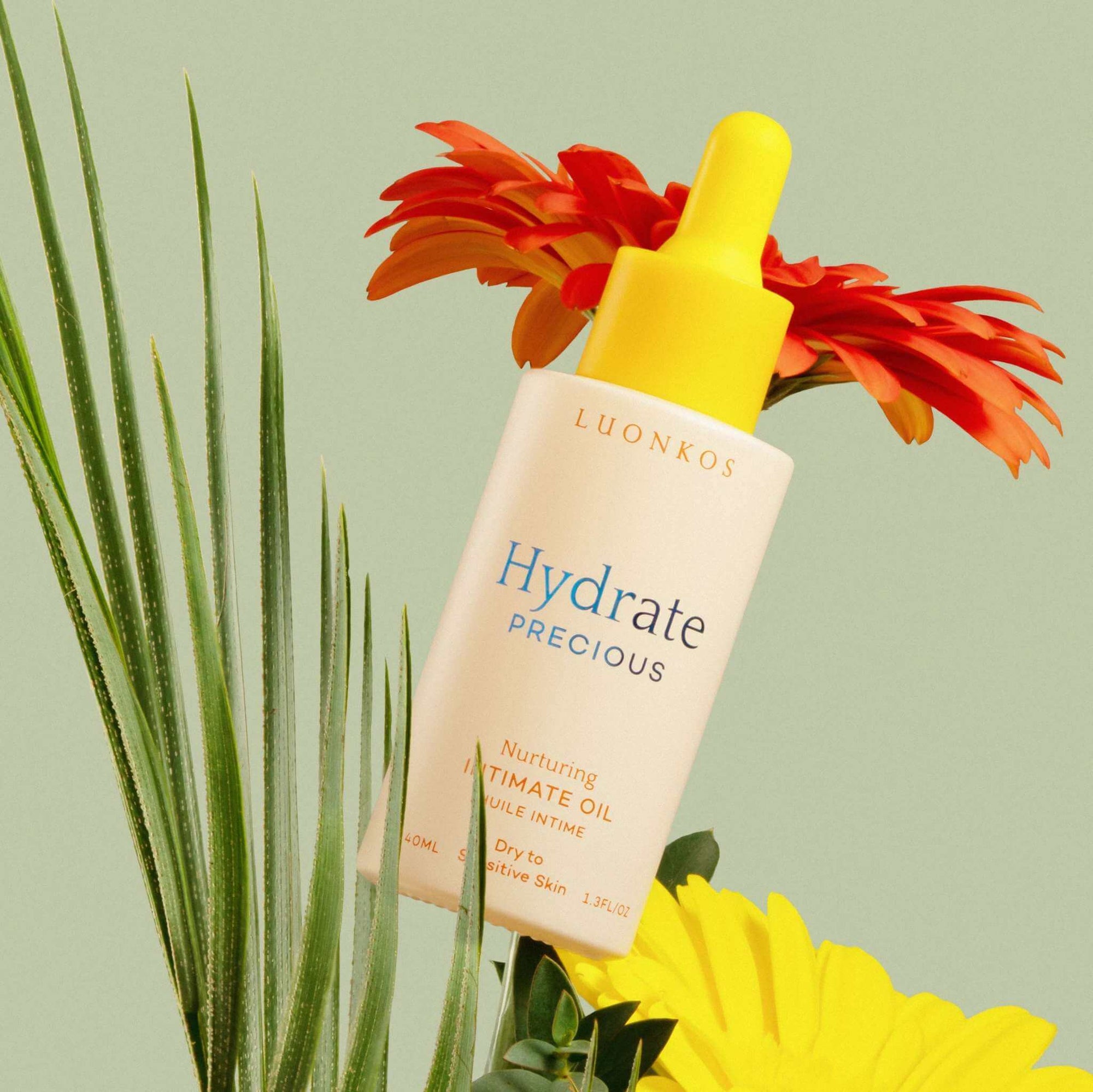 Luonkos Hydrate Precious nurturing intimate oil for dry and sensitive skin with yellow dropper and colorful flowers background, natural menopause skincare product
