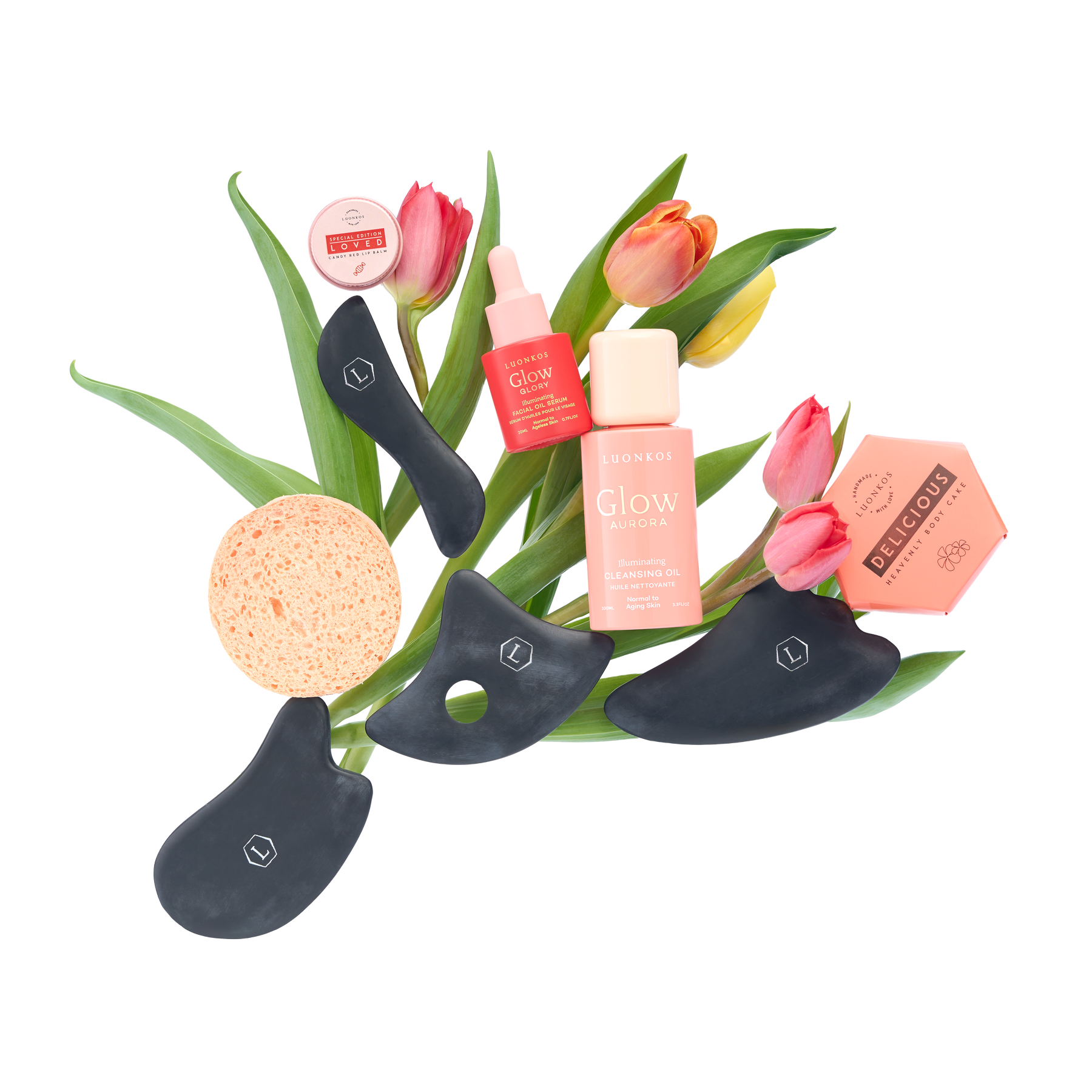 Luonkos kevätboksi – Glow-puhdistusöljy, Delicious-vartaloöljykakku, Guasha-kivet, kasvosieni ja Loved-huulivoide tulppaanikimpun ympäröimänä
