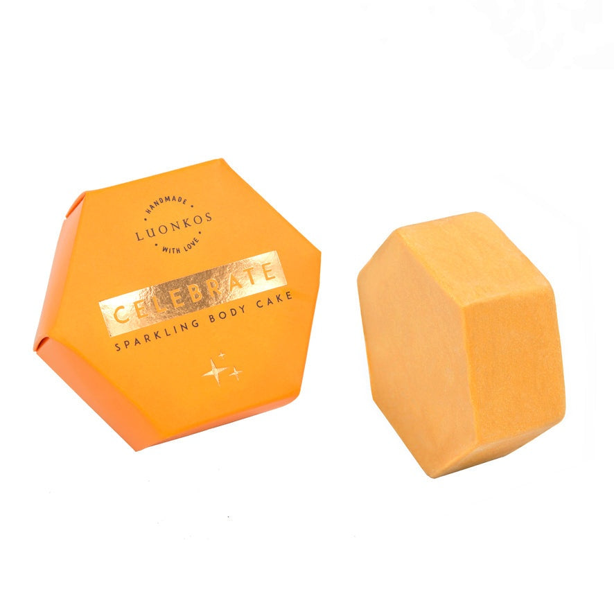 Celebrate sparkling body oil cake in hexagonal orange packaging for hydrating and glowing skin
